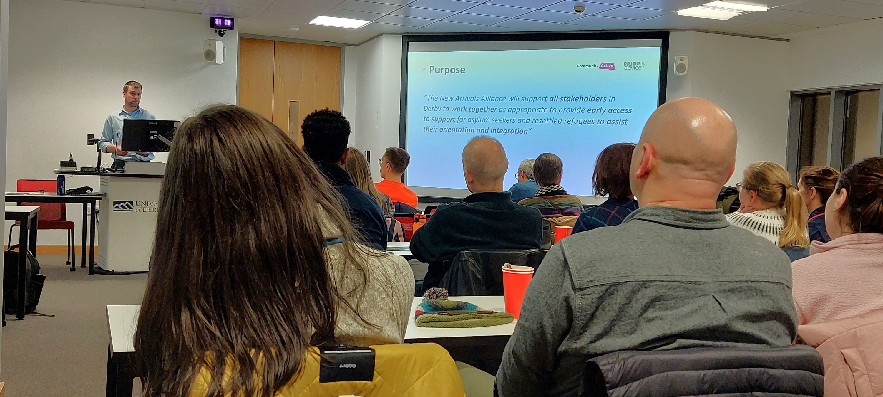 ting a slide on the purpose of the NAA at the New Arrivals Alliance Research Launch Event