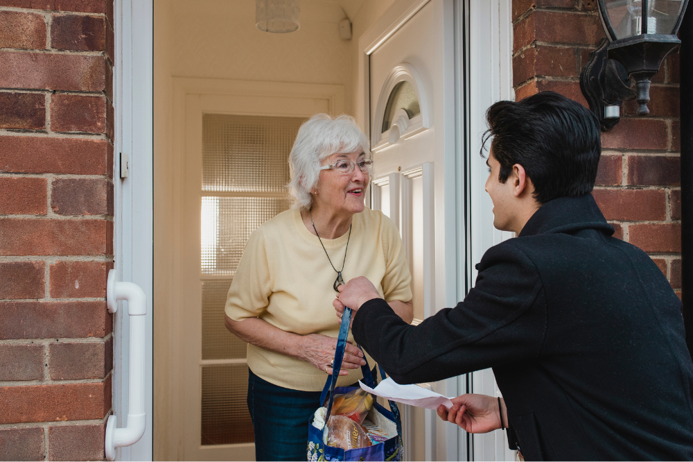 A volunteer bringing shopping to an older lady at her house
