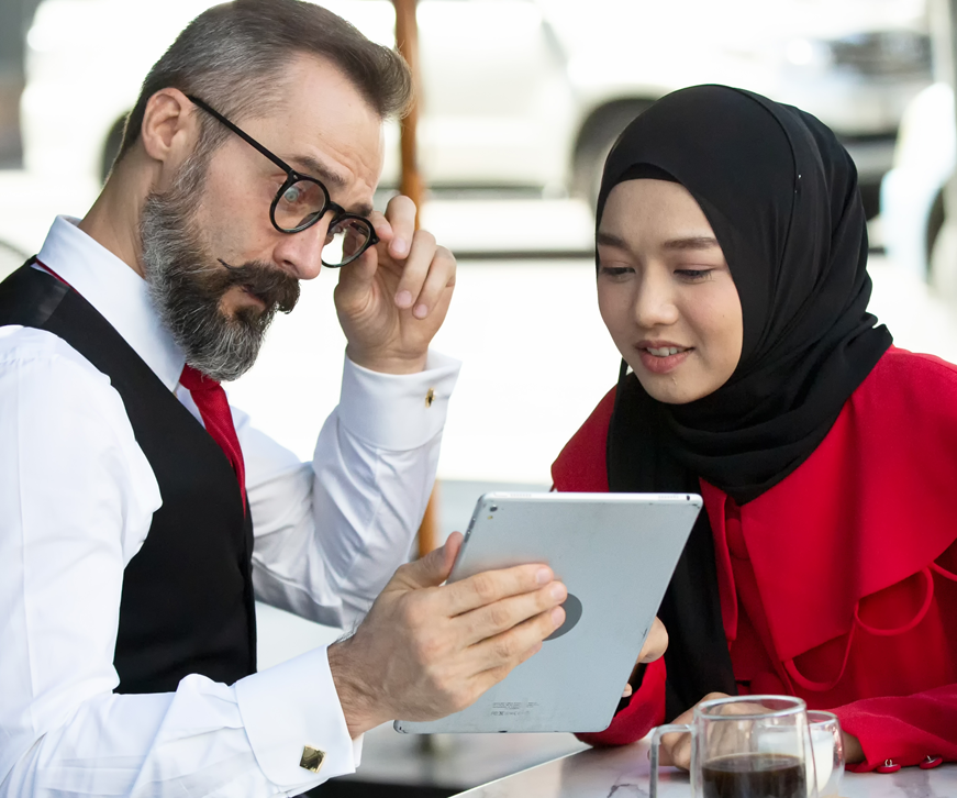A lady in a hijab helping a man to use his iPad
