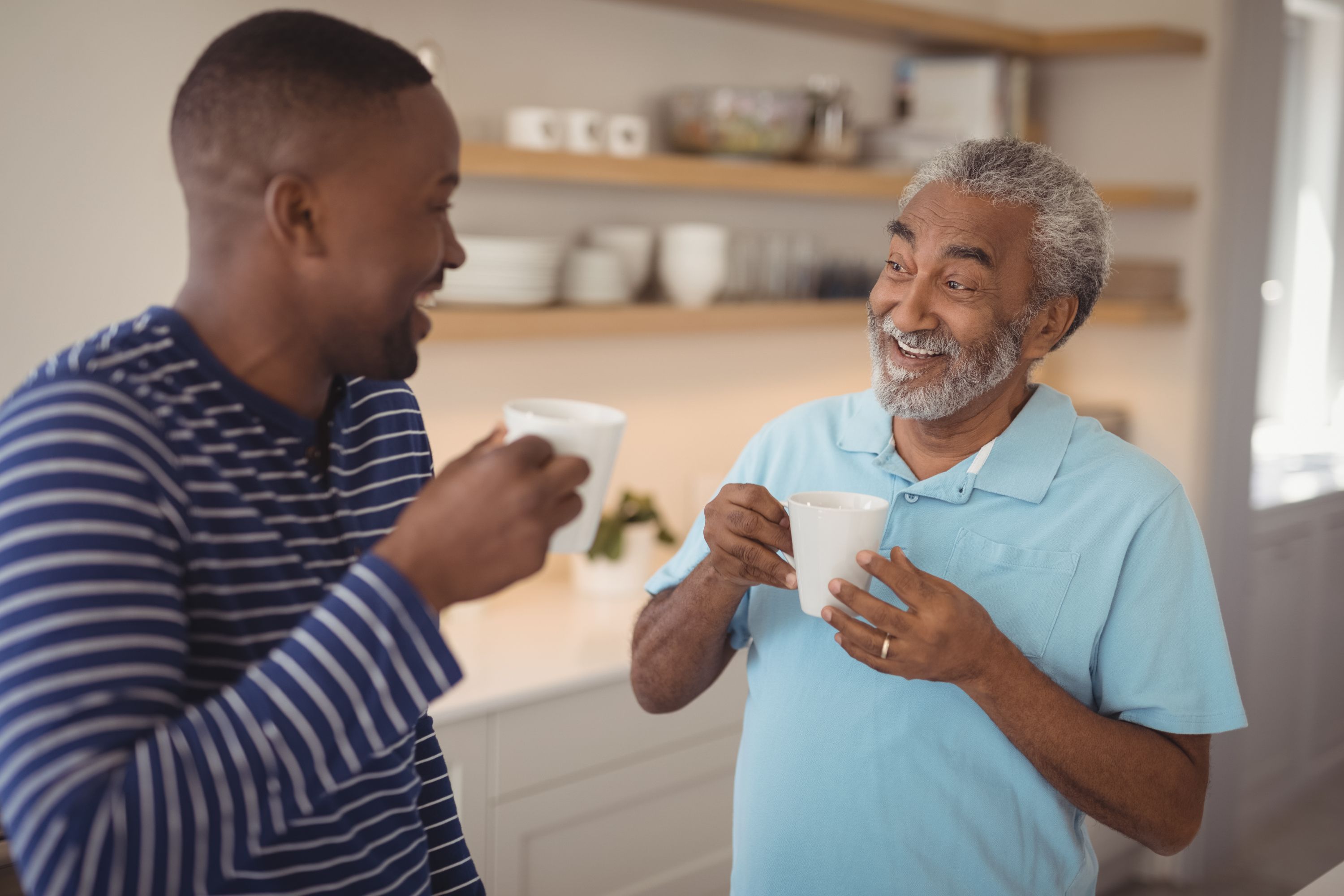Two black men having a cup of tea and laughing together
